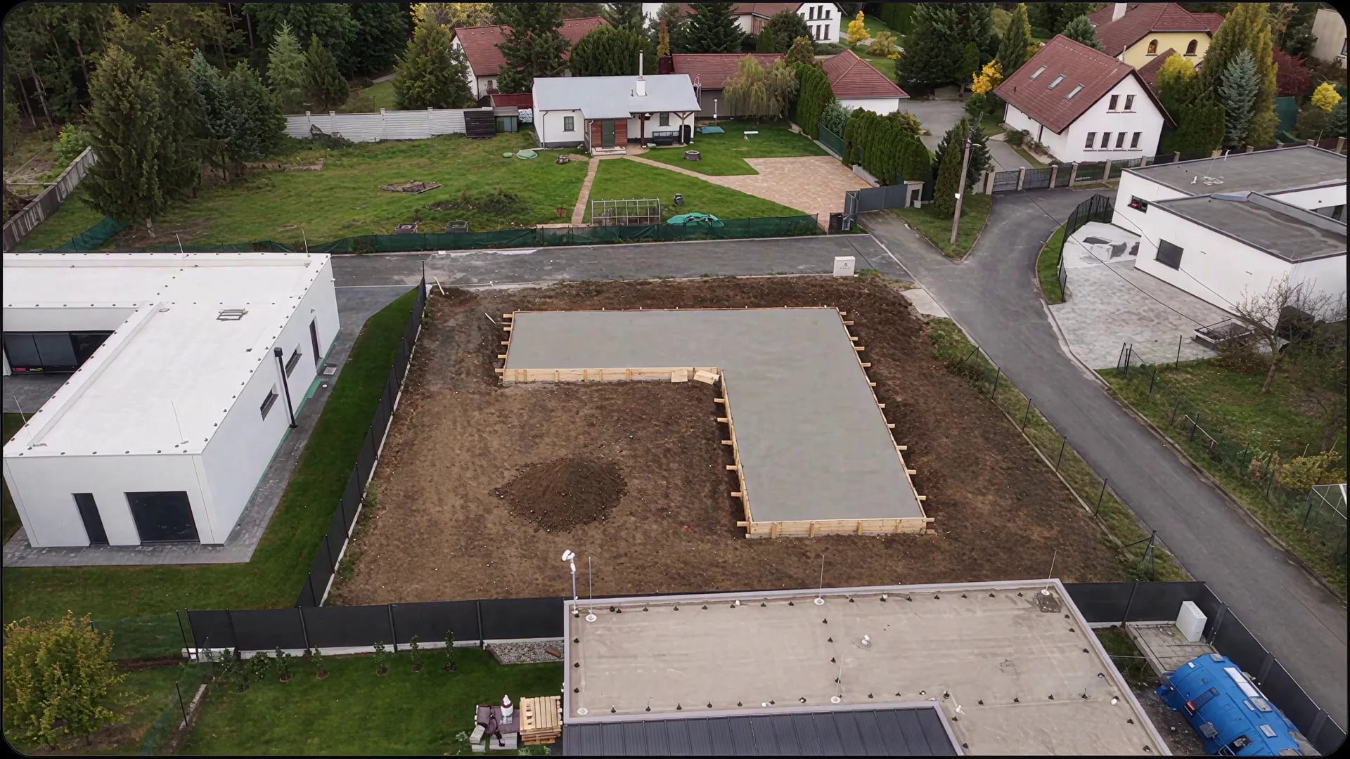 Pohled z dronu na základovou desku domu ve tvaru L mezi okolní zástavbou v Bartovicích